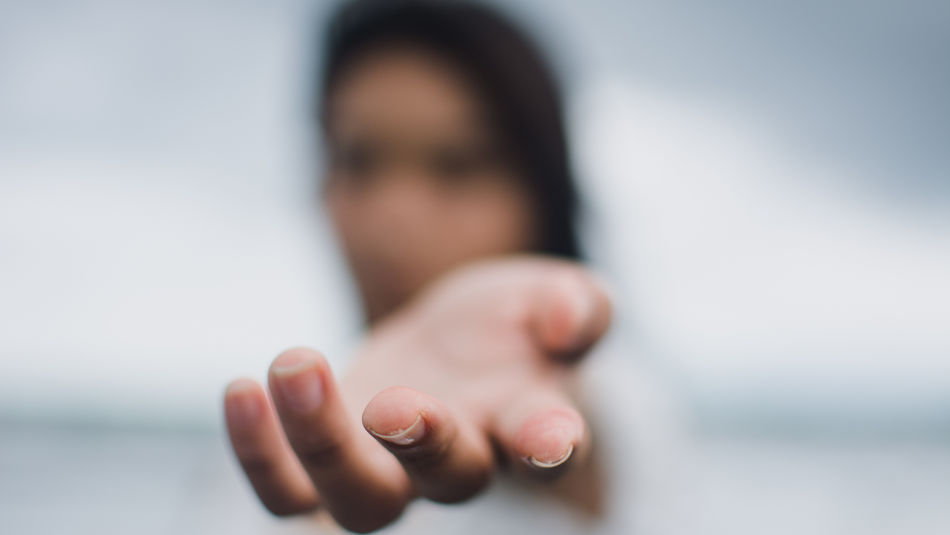 Eine Person streckt ihren Arm nach vorne aus. Die Person ist verschwommen dargestellt.