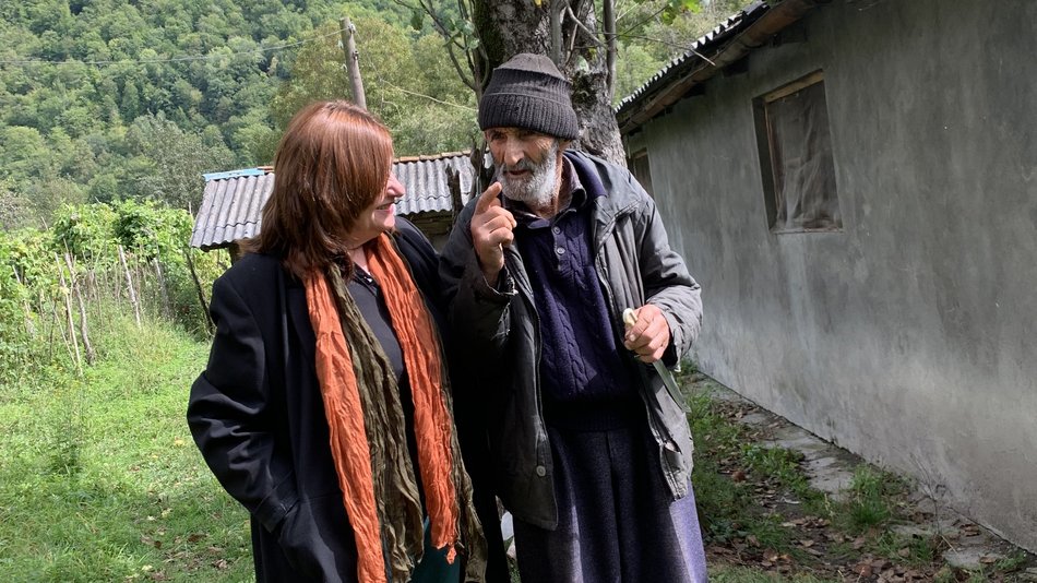 Bild zeigt zwei Menschen die sich auf einer grünen Wiese unterhalten