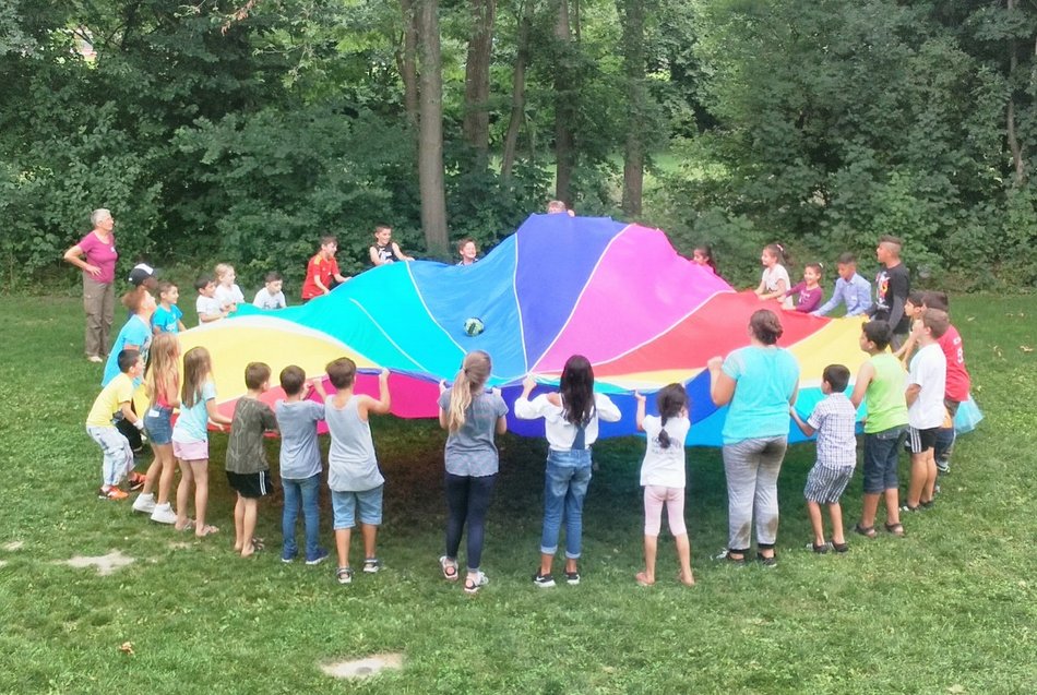 Bild zeigt viele Kinder beim zusammen spielen mit einem Fallschirm