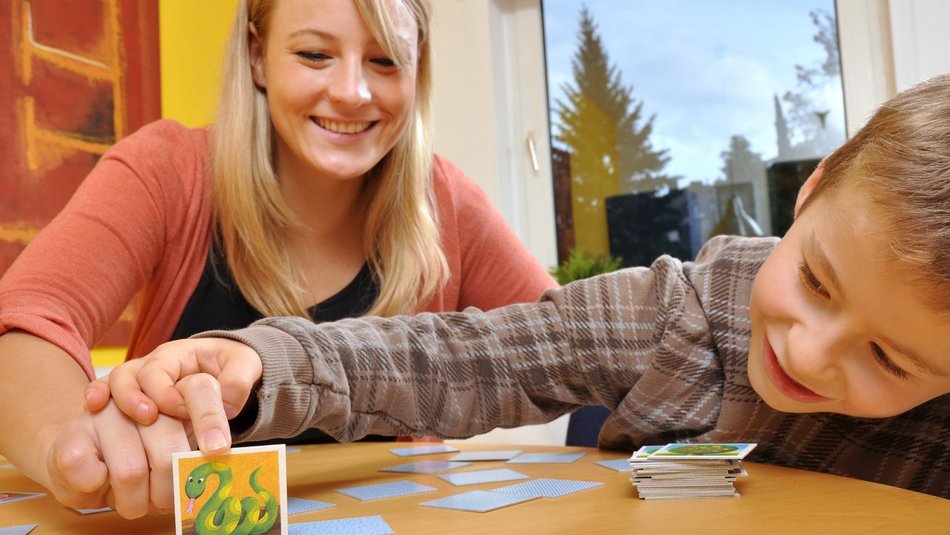 Eine junge Frau die mit einem Jungen Memorie spielt
