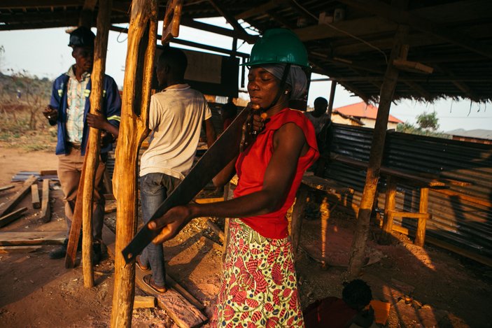 Drei Personen bauen an einer Hütte aus Holz.