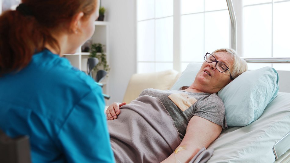 Bild zeigt eine Bett liegende Frau die von einer Schwester versorgt wird 