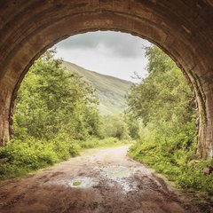 Bild zeigt den Blick aus einem dunklen Tunnel in eine helle und grüne Landschaft