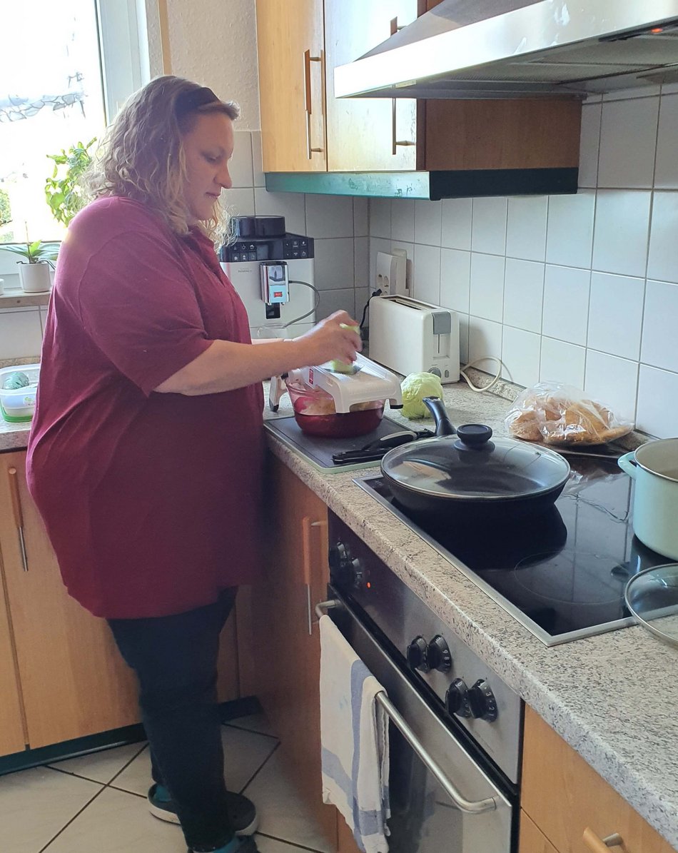 Eine Familienpflegerin bereitet in der Küche Essen zu.