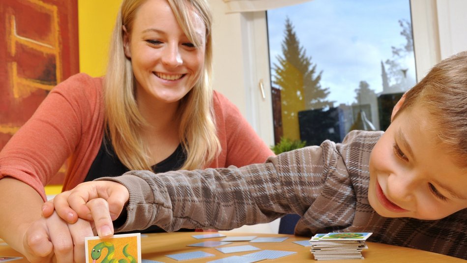 Eine junge Frau die mit einem Jungen Memorie spielt