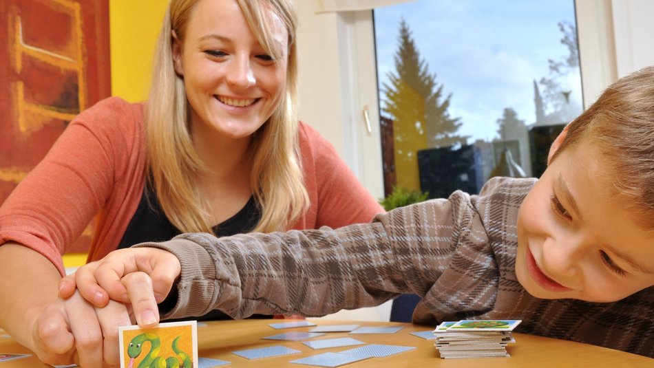 Eine junge Frau die mit einem Jungen Memorie spielt
