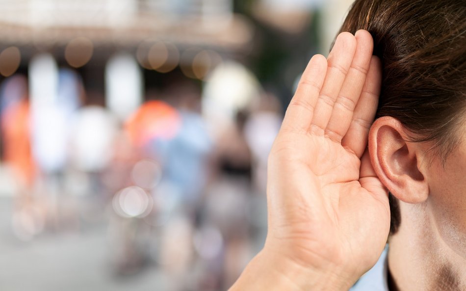 Bild zeigt eine Hand die sich offen vor ein Ohr hebt