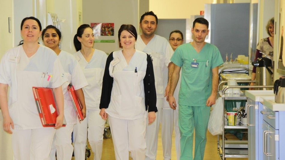 Bild zeigt eine Gruppe von Pfeger:innen bei der Visite in einem Krankenhaus
