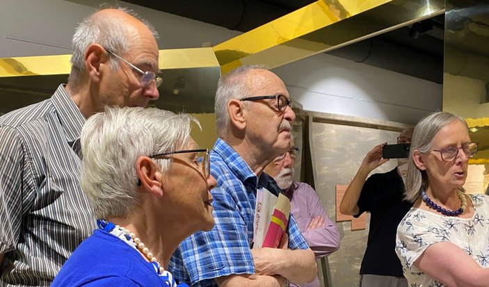 Bild zeigt Teilnehmer die angespannt zuhören im stehen in einer Austellung