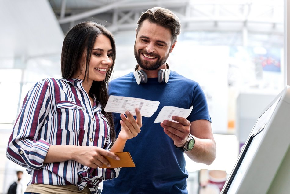 Eine Frau und ein Mann schauen lachend auf ihre Einreisepapiere.