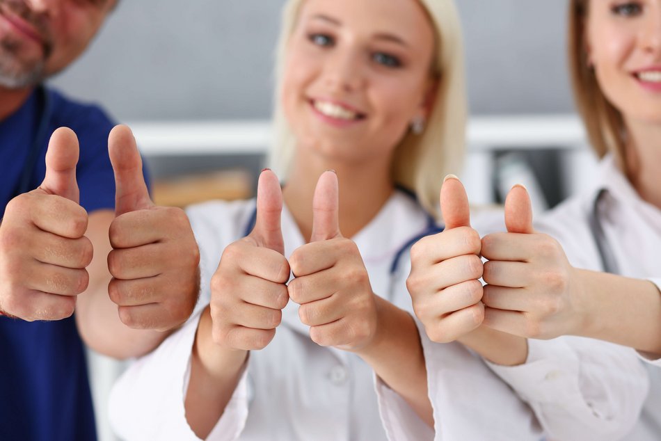 Bild zeigt drei Pflegemitarbeiter die jeweils beide Daumen nach oben strecken