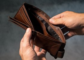 Ein Mann blickt von oben in einen leeren Geldbeutel.