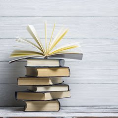 Ein Stapel aus sechs Büchern, das oberste ist aufgeklappt.