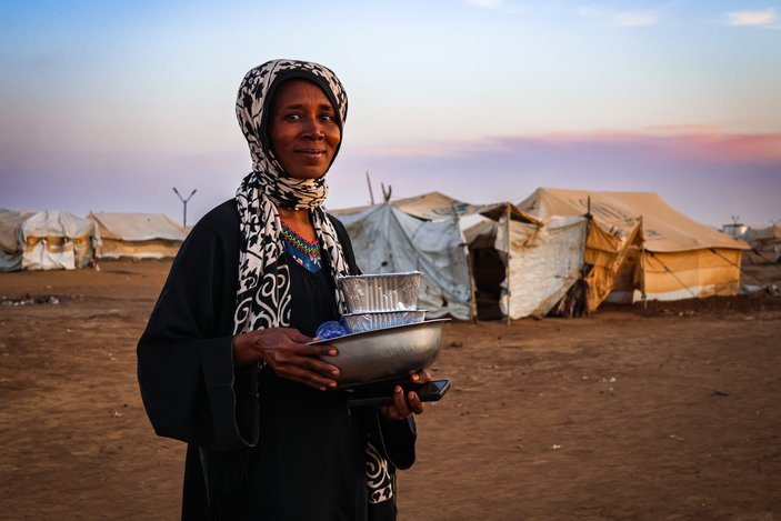 Frau im Sudan mit Waren des täglichen Bedarfs in den Händen