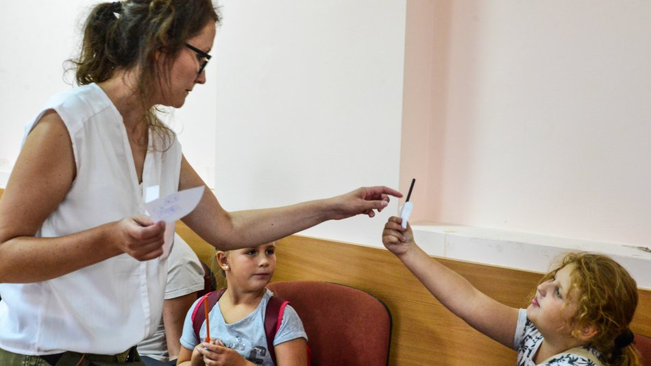 Bild zeigt eine Frau die von einem Kind etwas gereicht bekommt