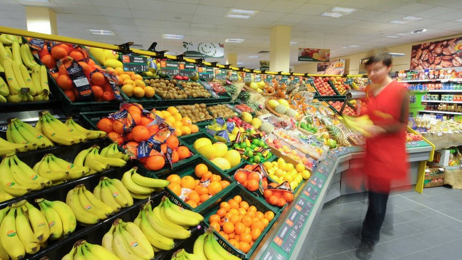 Eine Verkäuferin im Obst- und Gemüsebereich im Supermarkt.