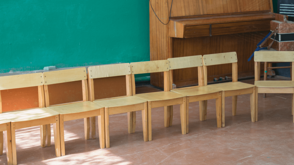 Bild zeigt mehrere leere Holzstühle die Nebeneinander stehen