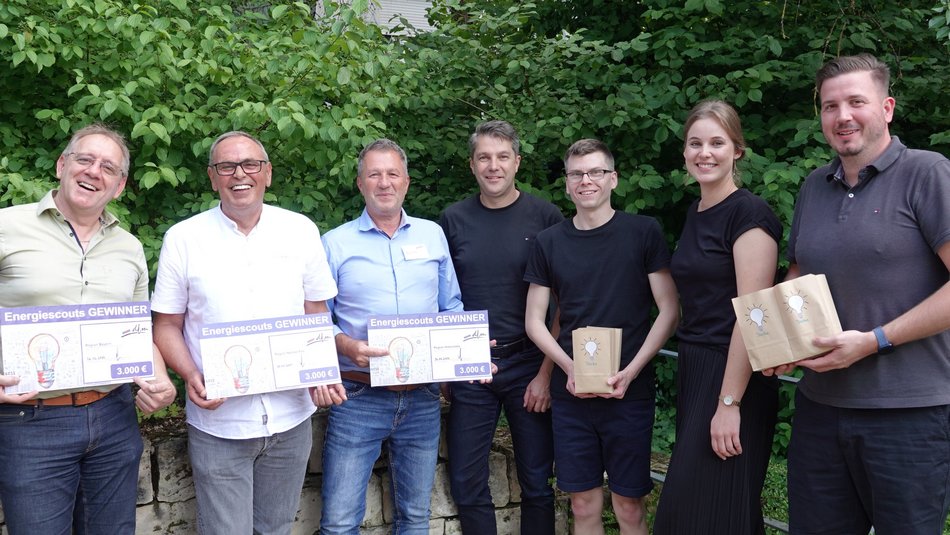 Sieben Personen halten im Freien Ihre Urkunde zum Energiescout in die Kamera.