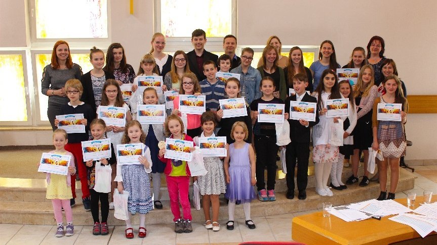 Bild zeigt ein Gruppenbild von Kindern die bunte Zettel nach oben halten