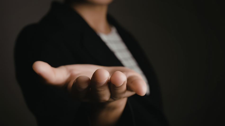 Eine Hand wird mit der Handfläche nach oben von einer Person nach vorne ins Bild ausgestreckt.