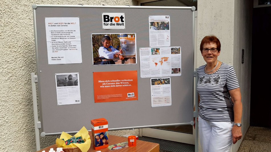 Eine Frau steht neben einem Tisch und Aufsteller mit Informationen zu Brot für die Welt.