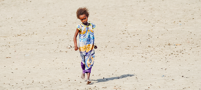 Bild zeigt ein bunt gekleidetes Kind in der Wüste laufen