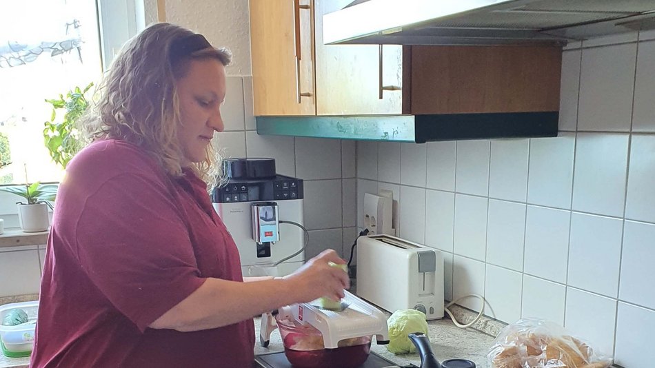 Eine Familienpflegerin bereitet in der Küche Essen zu.