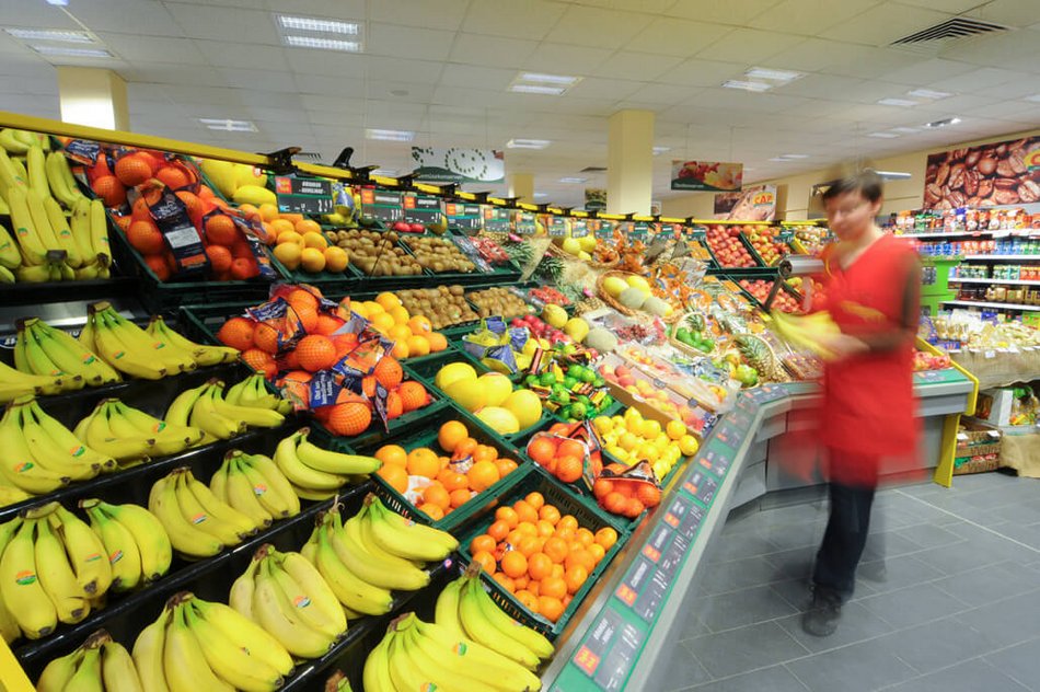 Eine Verkäuferin im Obst- und Gemüsebereich im Supermarkt.