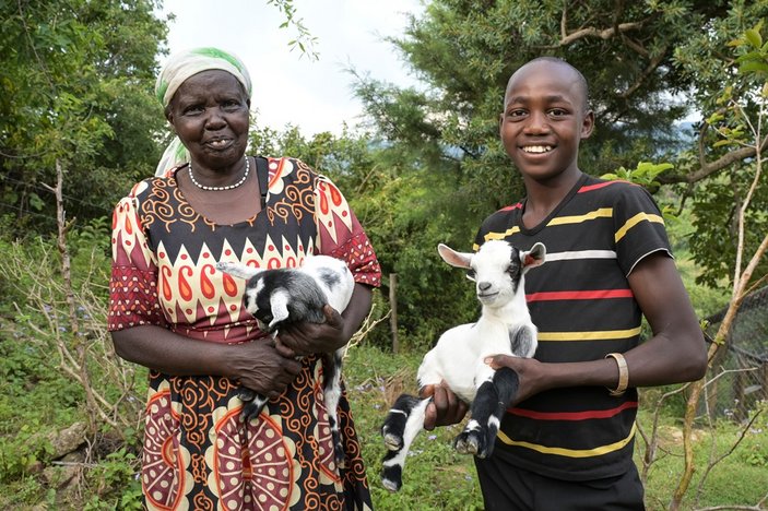 Bild zeigt eine kenianische Mutter mit ihrem Sohn, beide haben eine kleine Ziege auf dem Arm
