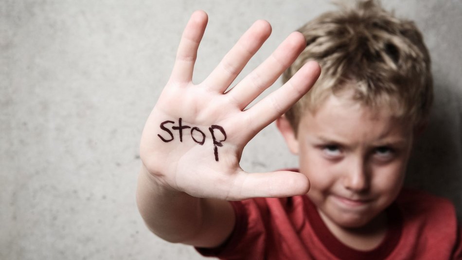 Bild zeigt einen Jungen der seine Hand in die Kamera zeigt mit dem Wort "Stop" 