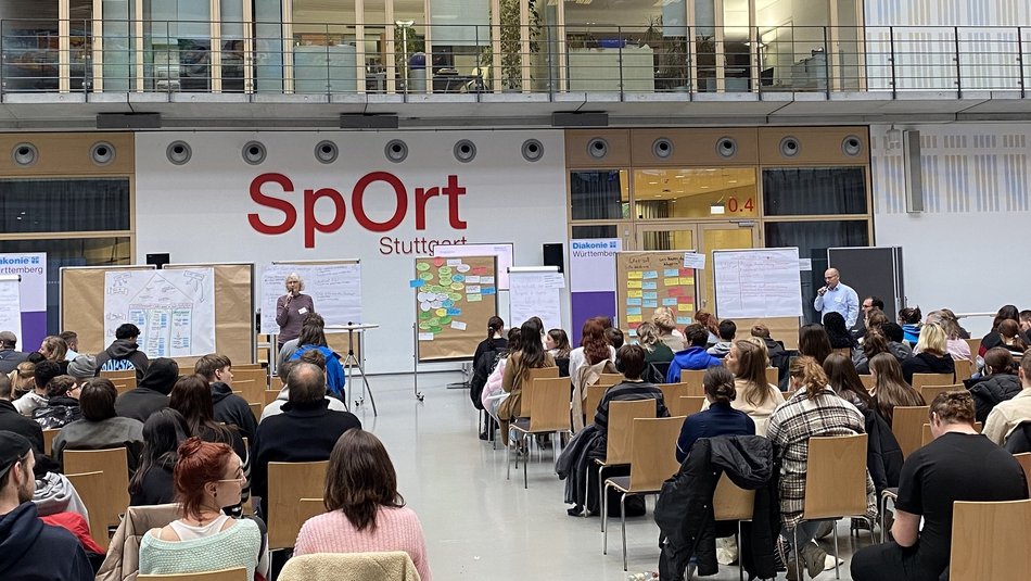 Bild zeigt die Teilnehmer die einem Vortrag in großer Runde teilnehmen