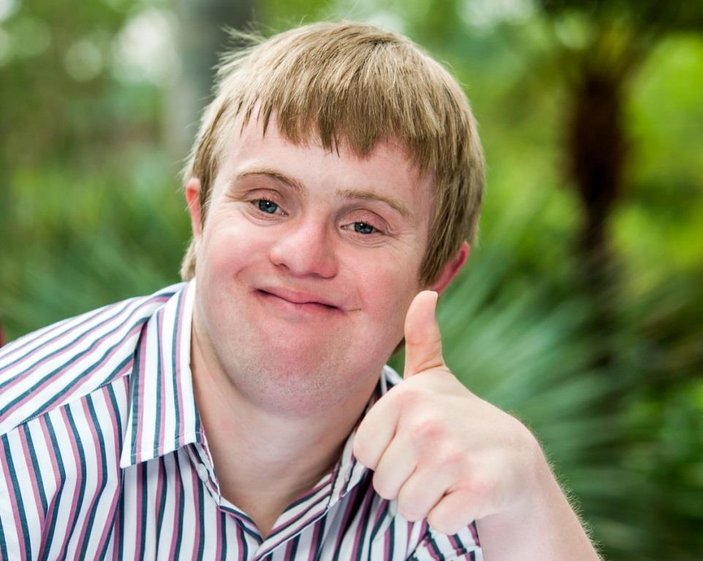 Bild zeigt einen jungen man mit Downsyndrom der eine "Daumen hoch" Geste macht