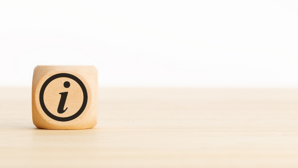 Ein Würfel mit dem Zeichen für Information liegt auf einem Tisch.