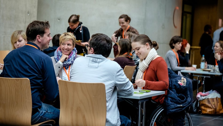 Mehrere Personen sitzen an Tischen und arbeiten zusammen.
