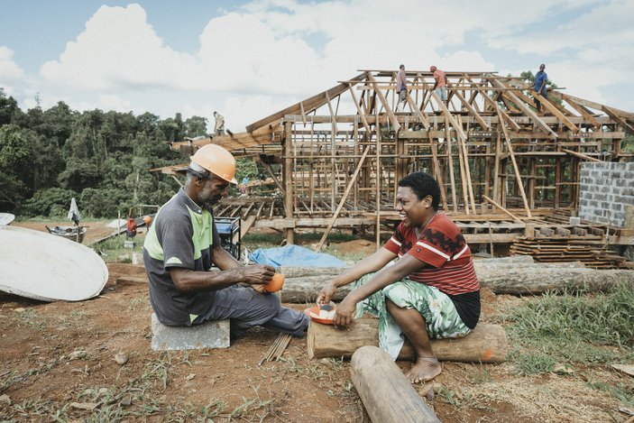 Bild zeigt zwei Arbeiter die vor einer Baustelle im Urwald sitzen