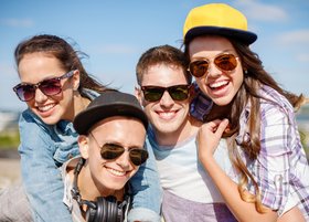 Eine Gruppe Jugendlicher mit Sonnenbrillen lacht in die Kamera.