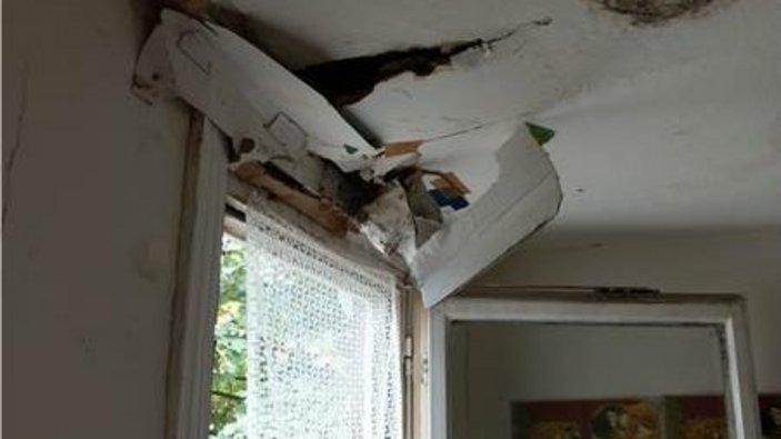 Über einem offenen Fenster mit Vorhang befindet sich eine beschädigte Raumdecke und Schimmel.