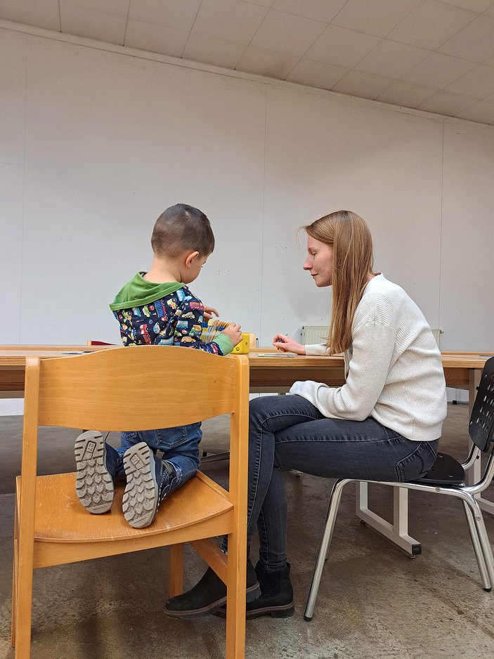 Es ist eine Frau mit einem kleinen Jungen zu sehen, die gemeinsam an einem Tisch sitzen. 