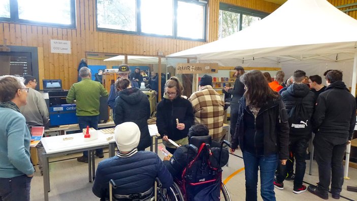 Mehrere Menschen stehen am Stand der Holzwerkstatt und der Schreinerei.