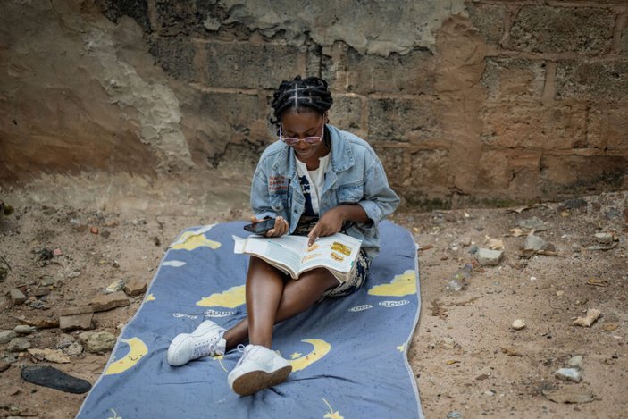 Bild zeigt eine junge Frau auf einer Decke die eine Zeitschrift anschaut