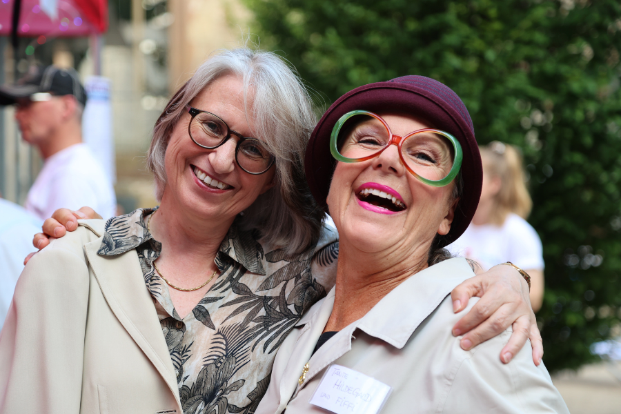 Dr. Annette Noller, Vorstandsvorsitzende Diakonie Württemberg, und Kabarettistin Sabine Schief lachen beim Benefiz-Abend 2025 in die Kamera.