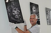 Matthias Rose hängt Portrait-Fotos im Eingangsbereich der Landesgeschäftsstelle auf.