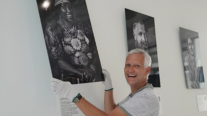 Matthias Rose hängt Portrait-Fotos im Eingangsbereich der Landesgeschäftsstelle auf.