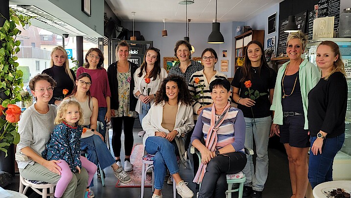 Fröhliche Frauen sitzen und stehen zum Gruppenfoto im Café