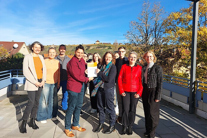 Bild zeigt ein Gruppenbild der Mitarbeiter der Einrichtung, die die Urkunde hoch halten