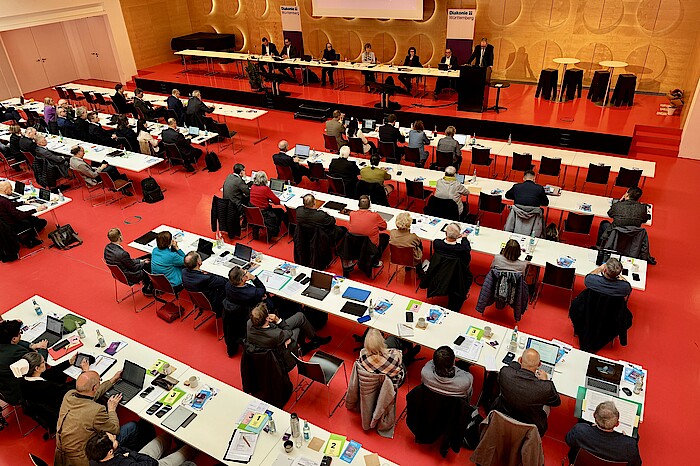 Blick von oben: Im großen Saal des Hospitalhofs sitzen viele Menschen mit Laptops an Tischen, auf der Bühne sitzen die Vorstands- und Präsidiumsmitglieder des DWW.