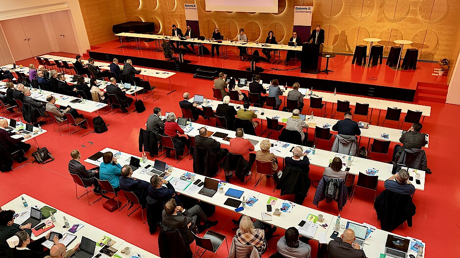Blick von oben: Im großen Saal des Hospitalhofs sitzen viele Menschen mit Laptops an Tischen, auf der Bühne sitzen die Vorstands- und Präsidiumsmitglieder des DWW.