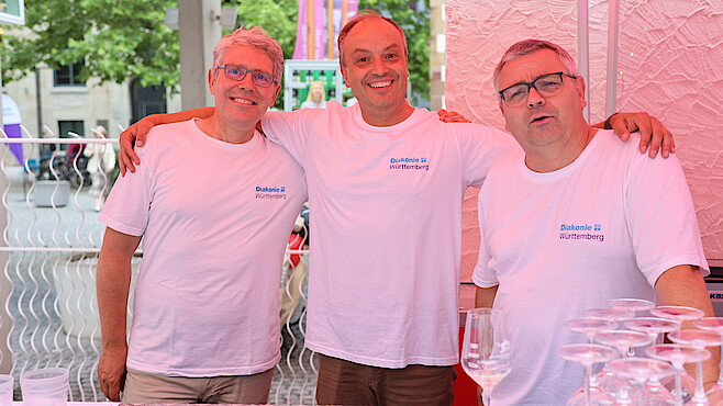 Drei Helfer an der Bar lächeln.