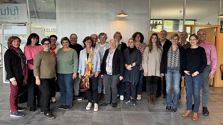Die Gruppe steht zusammen im Vorraum des futurums in Stuttgart und lächelt.