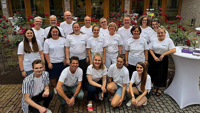 Etwa 20 Personen stehen mit weißen Diakonie-Shirts zusammen